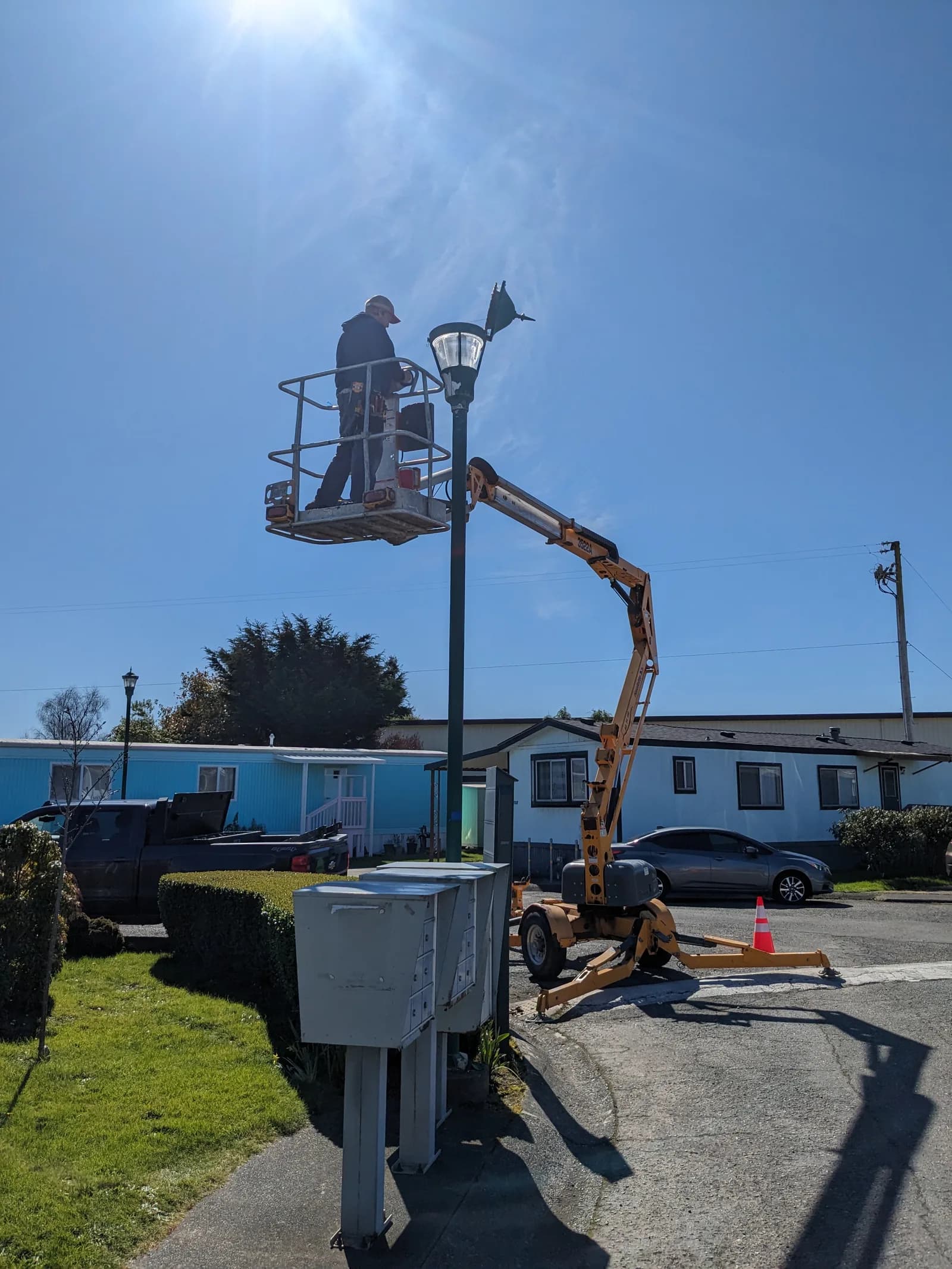 Greenbelt electrician in a boom lift repairing a street light in a Humboldt County neighborhood