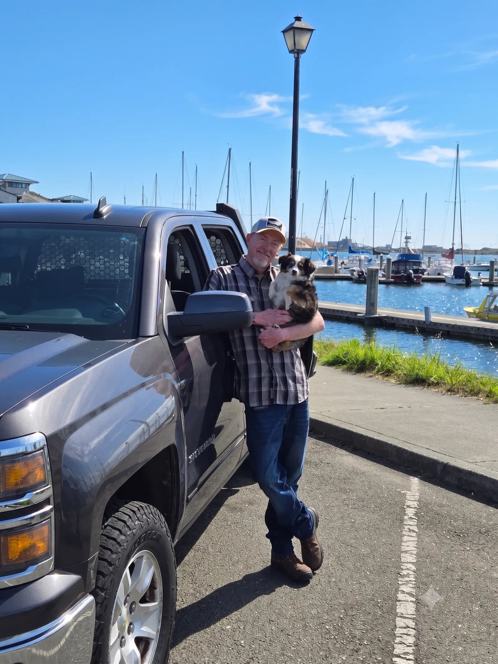 Ross, owner of Greenbelt Electrical, with his dog in front of his work truck at the Humboldt Bay marina in Eureka, CA